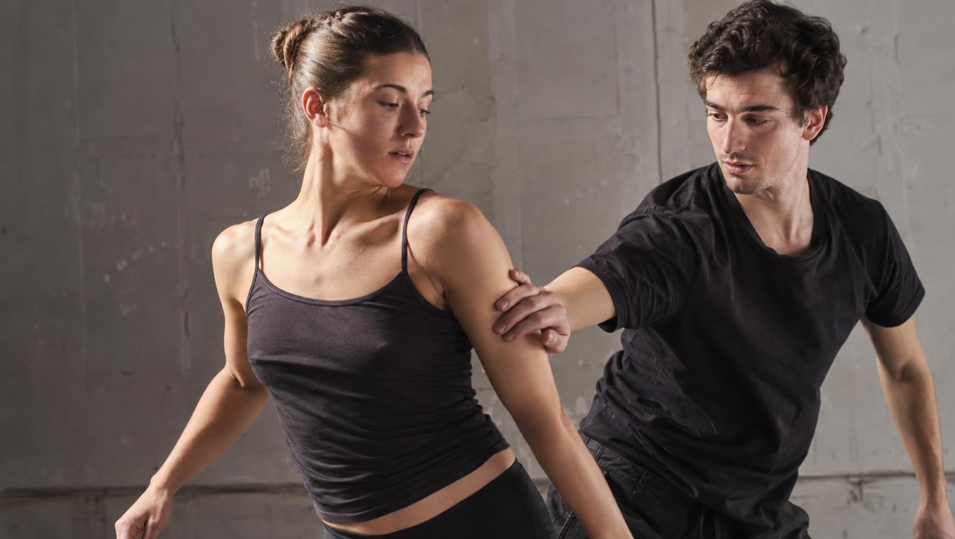Partners coordinate a demanding turn in a sunlit rehearsal hall
